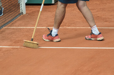 Man cleans tennis line on clay court