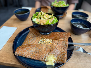 Traditional Crepe Galette made from buckwheat flour with cheese and nuts on a plate with salad in...