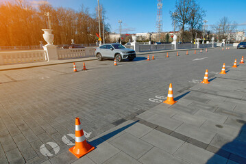 Cones arranged in row to designate and secure parking spots. Organized row of plastic traffic cones...