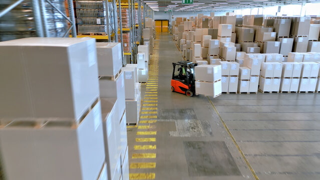 A forklift navigates an expansive warehouse, highlighting the global supply chain's efficiency and logistics' precision.