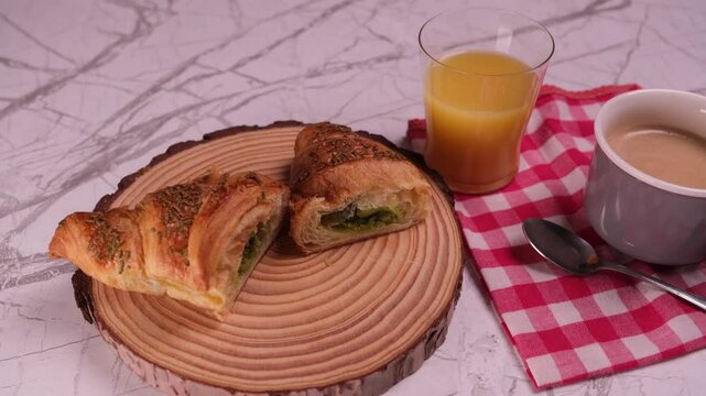 Cornetto ripieno di crema al pistacchio tagliato a met&agrave;, bicchiere di aranciata e tazzina di caff&egrave;