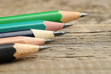 Different graphite pencils on wooden table, closeup