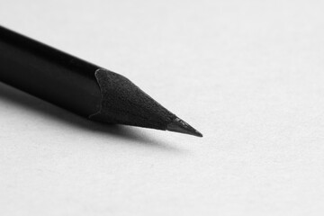 One sharp graphite pencil on light background, closeup. Space for text