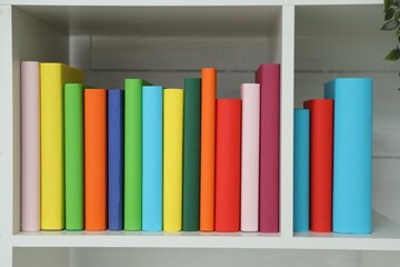 Colorful books on shelving unit indoors, closeup