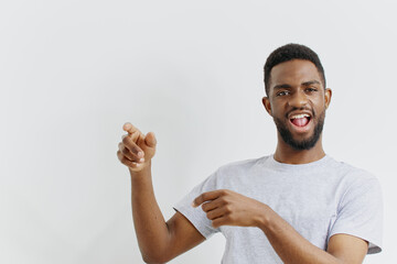 Confident young african american man gesturing with finger pointing towards camera against plain...