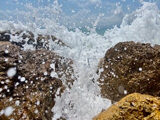 Obraz premium Ocean waves crashing against rocks on sunny day