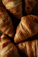 Fresh tasty croissants on wooden table, top view close-up. Baking, bakery