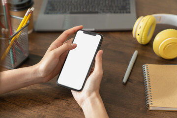 Hand holding smartphone with a blank screen on table, for putting advertising to promote.