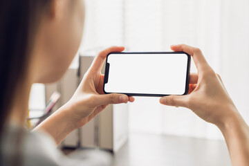 Hand holding smartphone with a blank screen on table, for putting advertising to promote.