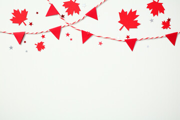Canada Day celebration flat lay. Red maple leaves and triangle paper bunting garland on white...