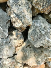 Close-up of a rough stone wall with natural textures and earthy tones. Ideal for backgrounds, construction themes, nature textures, or rustic design elements