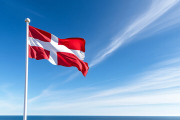 Fototapeta premium Bright Swedish flag waving in the wind against a clear blue sky by the ocean