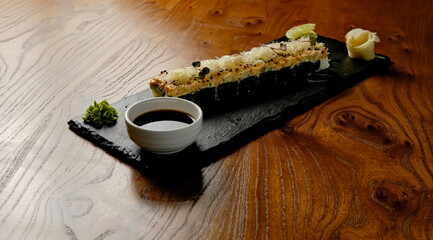 a sushi roll on a black board with soy sauce, lime, wasabi