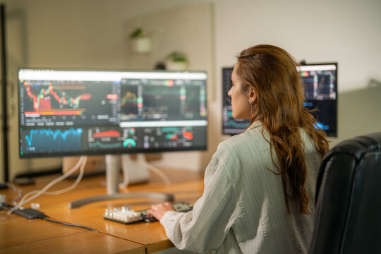 Woman analyzes stock market trends on multiple monitors in a modern workspace during daytime