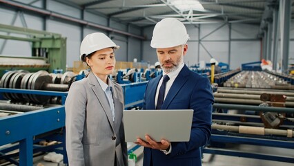 Male contractor communicating with colleague. Man in suit and helmet holding laptop. Industry...