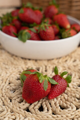 Several pieces of ripe strawberries on a blurred background of strawberries in a white plate. Dietary nutrition. Fresh seasonal berries.