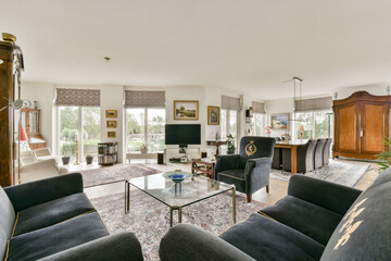 A stylish and modern lounge interior characterized by ample natural light, contemporary furniture,...
