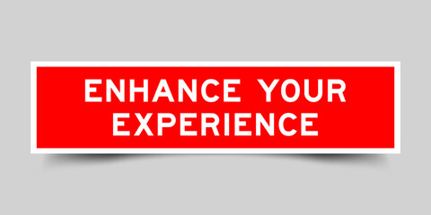 Red color square shape sticker label with word enhance your experience on gray background