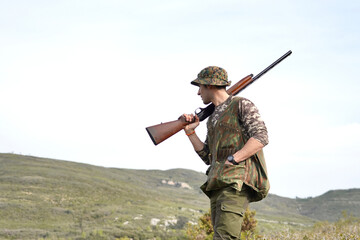A man in camouflage is holding a shotgun