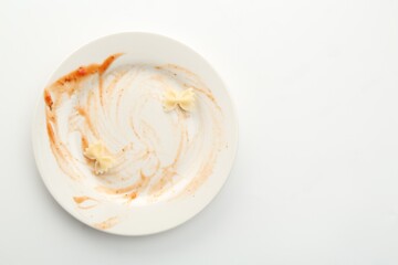 Dirty plate on white background, top view. Space for text