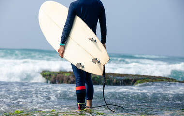 Woman surfer with surfboard going to surf at seaside