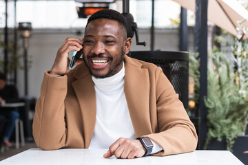 Man with black skin talking on phone while sitting on hotel terrace
