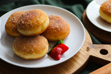 A handmade bombolone or bomboloni is an Italian-filled doughnut that is eaten as a snack or dessert. Selective focus.