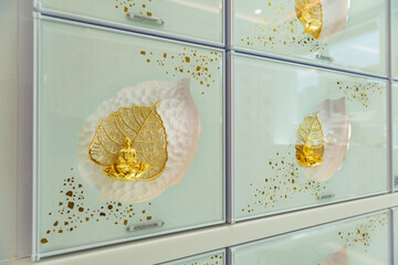 Close-up of columbarium niche with golden seated Buddha figure and sacred Bodhi leaf motif,...