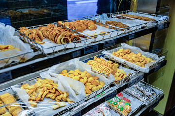 Display case filled with assorted cookies and pastries in a Taiwanese bakery, including almond cookies, palmiers, and iced character treats