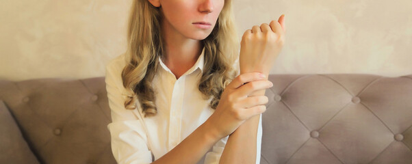 Unhealthy young woman suffers from wrist pain, tunnel syndrome, unwell girl touching her hand
