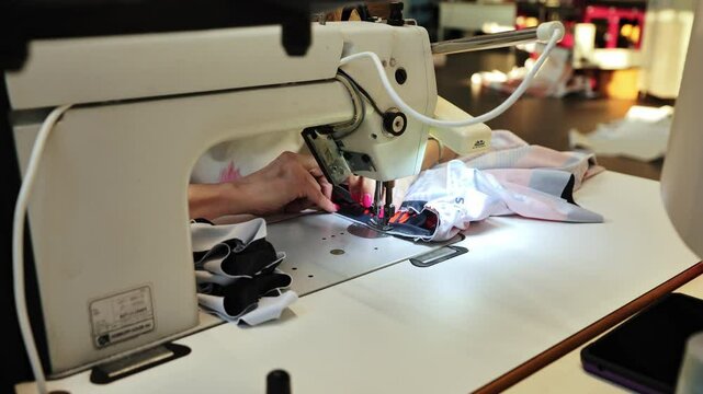 Slow motion close-up of woman sewing performance fabric in a professional studio