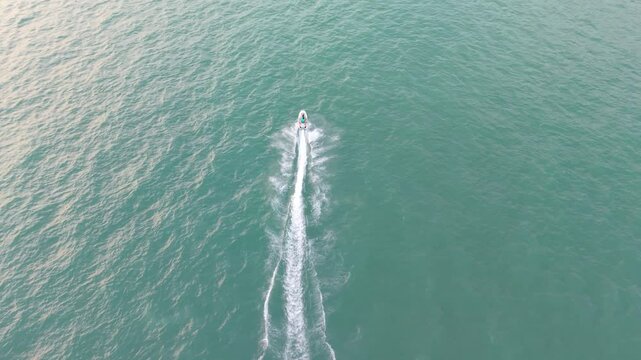 Powerful white motorboat slicing through turquoise waters, generating dramatic foamy wake during high speed maritime journey under bright sunshine