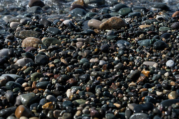 Pebble beach on the shore of the Black Sea. Colorful pebble stones on the seashore as a background
