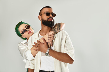 Stylish multicultural couple showcases trendy sunglasses in contemporary studio space