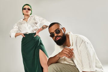Stylish multicultural couple showcasing bold fashion choices in modern studio