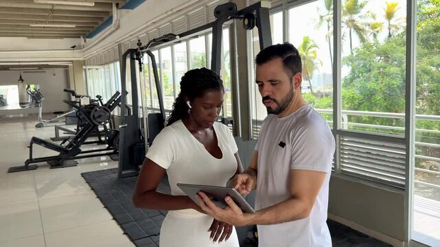 Personal trainer showing tablet to client in gym