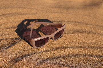 Sunglasses on sand, beach summer accessory, trendy eyewear