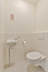 A minimalist bathroom featuring white tiles, a sleek sink, and modern toilet. The design focuses on simplicity and clean lines in a small space.