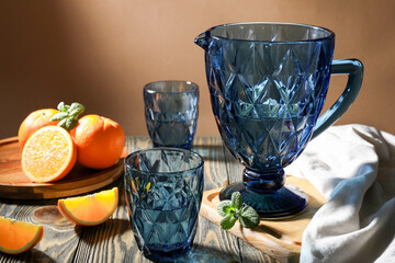 Blue faceted jug and glasses filled with water with oranges