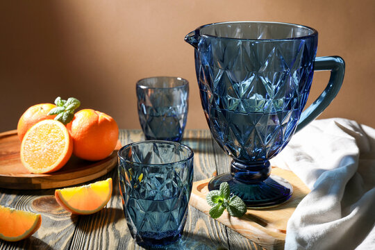 Blue faceted jug and glasses filled with water with oranges