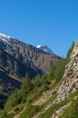 Alpine meadows spread out at foot of snow-capped peaks. Kabardino-Balkaria. View of snow-capped peaks of Chegem Gorge. Majestic natural landscapes of Elbrus region against backdrop of blue autumn sky