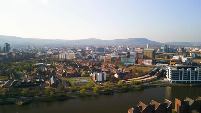 Rising aerial shot of the River Lagan in Belfast on a bright, sunny summer day. The camera takes in the Lower Ormeau area, Ormeau Park and the river. Filmed in 4K, 60fps and with Rec709 Color.