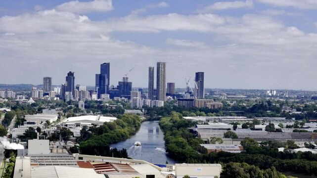 An expansive shot of Parramatta, Sydney, featuring a prominent river winding through the cityscape, flanked by trees and leading towards a cluster of modern skyscrapers