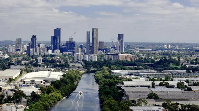An expansive shot of Parramatta, Sydney, featuring a prominent river winding through the cityscape, flanked by trees and leading towards a cluster of modern skyscrapers
