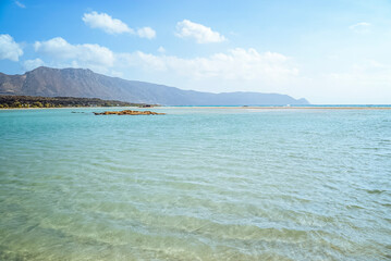 Obraz premium Elafonissi Beach, Crete, Island, Greece: Turquoise water meets mountains under a cloudy sky