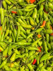 Pile of fresh green chili peppers, Green and red hot chili peppers on a market stall in thailand.