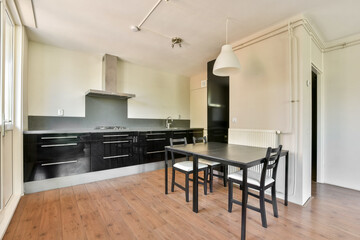 A sleek and modern kitchen featuring dark cabinetry, minimalistic design, and a small dining area, showcasing a clean and functional aesthetic.