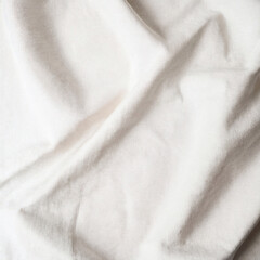 Natural white cotton linen fabric background. Soft plain textile top view surface earth tone color. Close-up texture of neutral white cloth for display products, mockups or presentations.