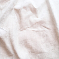 Natural white cotton linen fabric background. Soft plain textile top view surface earth tone color. Close-up texture of neutral white cloth for display products, mockups or presentations.