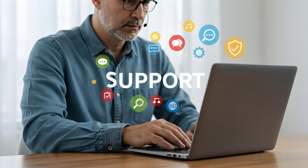 Man with headset using laptop with support text and icons overlayed on a wooden desk in a bright room